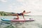 Middle age Caucasian woman practising yoga on paddle sup surfboard at sunset.