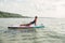 Middle age Caucasian woman practising yoga on paddle sup surfboard at sunset.