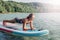 Middle age Caucasian woman sitting riding on paddle sup surfboard at sunset.