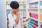 Middle age chinese woman customer holding shampoo bottle at pharmacy