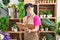 Middle age chinese woman florist reading notebook with doubt expression at flower shop