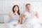 Middle age couple in bedroom lying in bed and showing big thumbs up. Happy family life and relationship. copy space