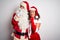 Middle age couple wearing Santa costume hugging over isolated white background Thinking worried about a question, concerned and