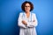 Middle age curly hair doctor woman wearing coat and stethoscope over blue background skeptic and nervous, disapproving expression