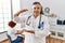 Middle age doctor man at the clinic with a patient gesturing with hands showing big and large size sign, measure symbol