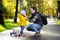 Middle age father helping his little son to put his helmet. Active toddler boy to ride a scooter.