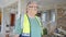 Middle age grey-haired man builder standing with relaxed expression at construction site