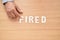 Middle age grey-haired man business worker sitting on table with fired word at office