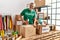 Middle age grey-haired man volunteer smiling confident packing books cardboard box at charity center