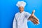 Middle age grey-haired man wearing professional cook uniform and hat smiling friendly offering handshake as greeting and welcoming