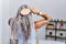 Middle age grey-haired woman on back view combing hair standing at home