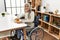 Middle age grey-haired woman eating classical hamburger sitting on wheelchair at home