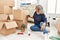 Middle age grey-haired woman writing books word on cardboard box at new home