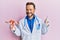 Middle age gynecologist man holding anatomical model of female genital organ smiling happy pointing with hand and finger to the