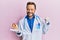Middle age gynecologist man holding anatomical model of female uterus with fetus pointing thumb up to the side smiling happy with