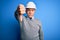 Middle age handsome grey-haired engineer man wearing safety helmet over blue background looking unhappy and angry showing