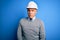 Middle age handsome grey-haired engineer man wearing safety helmet over blue background skeptic and nervous, frowning upset