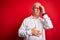 Middle age handsome hoary man wearing casual shirt and glasses over red background Touching forehead for illness and fever, flu