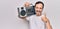 Middle age handsome man listening vintage boombox over isolated white background smiling happy and positive, thumb up doing