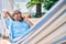 Middle age handsome man at the terrace of his house relaxing lying on a hammock speaking on the phone