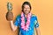 Middle age handsome man wearing hawaiian lei holding pineapple looking positive and happy standing and smiling with a confident