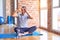 Middle age handsome sportman sitting on mat doing stretching yoga exercise at gym Doing heart shape with hand and fingers smiling