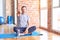 Middle age handsome sportman sitting on mat doing stretching yoga exercise at gym looking unhappy and angry showing rejection and