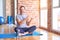 Middle age handsome sportman sitting on mat doing stretching yoga exercise at gym Showing palm hand and doing ok gesture with