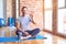 Middle age handsome sportman sitting on mat doing stretching yoga exercise at gym showing and pointing up with fingers number five