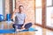 Middle age handsome sportman sitting on mat doing stretching yoga exercise at gym smiling and confident gesturing with hand doing