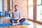 Middle age handsome sportman sitting on mat doing stretching yoga exercise at gym smiling doing phone gesture with hand and