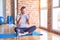 Middle age handsome sportman sitting on mat doing stretching yoga exercise at gym smiling doing talking on the telephone gesture