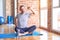 Middle age handsome sportman sitting on mat doing stretching yoga exercise at gym stretching back, tired and relaxed, sleepy and