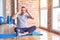 Middle age handsome sportman sitting on mat doing stretching yoga exercise at gym Trying to open eyes with fingers, sleepy and