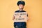 Middle age hispanic man wearing police uniform holding we need a change banner making fish face with mouth and squinting eyes,