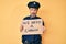 Middle age hispanic man wearing police uniform holding we need a change banner relaxed with serious expression on face
