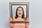 Middle age hispanic woman holding empty frame smiling and laughing hard out loud because funny crazy joke