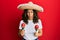 Middle age hispanic woman holding mexican hat playing maracas clueless and confused expression