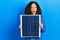 Middle age hispanic woman holding photovoltaic solar panel celebrating crazy and amazed for success with open eyes screaming