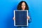 Middle age hispanic woman holding photovoltaic solar panel relaxed with serious expression on face