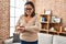 Middle age hispanic woman looking smartwatch standing at home