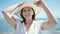 Middle age hispanic woman tourist smiling holding summer hat at the beach