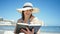 Middle age hispanic woman tourist sunbathing sitting on the towel reading a book at the beach