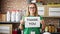 Middle age hispanic woman volunteer holding thank you message on paper at charity center