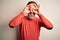 Middle age hoary man wearing casual orange sweater standing over isolated white background doing ok gesture like binoculars