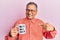 Middle age indian man drinking mug of coffee with best dad ever message smiling happy pointing with hand and finger