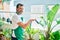 Middle age man with beard smiling happy watering the plants at the terrace