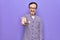 Middle age man changing tv channel using television remote control over purple background looking positive and happy standing and