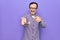 Middle age man changing tv channel using television remote control over purple background smiling happy pointing with hand and