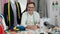 Middle age man tailor smiling confident sitting on table at tailor shop